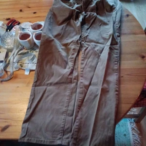 Bruna chinos stl 33/30 - Säljer ett par bruna chinos i bra skick. De har en normal passform och är perfekta för både vardag och lite mer uppklädda tillfällen. Byxorna har knappar och dragkedja framtill. Materialet känns slitstarkt och bekvämt. Perfekta för höst och vår! Stl 33/30