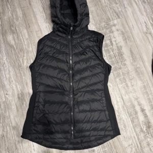 Svart dunväst från Kari Traa - Säljer en snygg svart dunväst från Kari Traa i storlek S. Västen har en praktisk dragkedja och en mysig huva, perfekt för kyliga dagar. Den är i mycket bra skick och passar utmärkt för höst och vinter. Perfekt för lager-på-lager-stil! Lite tunnare inte så tjock. 