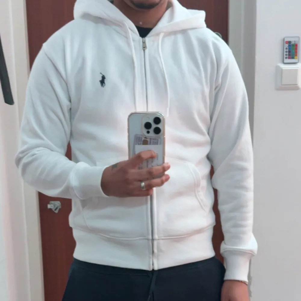 Säljer en snygg vit hoodie från Ralph Lauren med dragkedja. Perfekt för både vardag och chill. Köpt från Zalando så den är äkta. Storlek S. Priset kan gå ner vid snabb affär. Säljer för den va för liten.. Tröjor & Koftor.