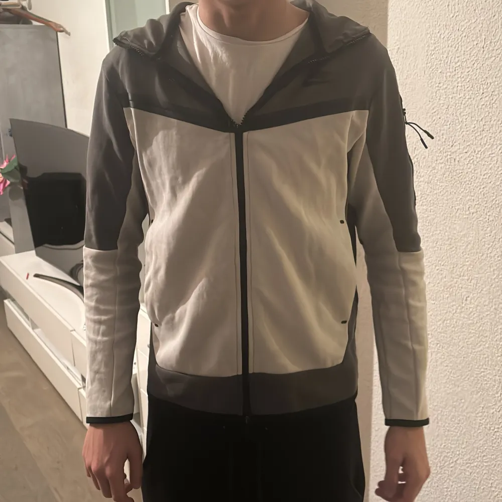 Säljer en snygg grå och vit jacka från Nike. Den har en dragkedja framtill och en huva för extra stil och komfort. Perfekt för vår och höst med sin långärmade design. Jackan är i bra skick och passar perfekt för en casual look.. Jackor.