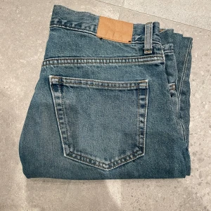 Blå jeans från Weekday - Säljer ett par snygga blå jeans från Weekday i modellen Space Relaxed Straight. Perfekta för en avslappnad stil och passar till alla tillfällen. Använda men i bra skick! Skirv vid funderingar.
