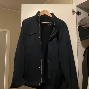 Mörkblå fieldjacket från J.Lindeberg - Säljer en stilren mörkblå jacka från J.Lindeberg i storlek L. Passar både till vardags och lite finare tillfällen. Med tanke på att denna model inte säljs längre så är priset lite högre med tanke på vad bra skick den har! Modellen på jackan heter BAILEY POLY JACKET ny priset på den låg på 3400kr men pris går att diskuteras!
