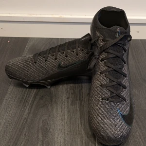 Nike Mercurial vapor 16 Elite - PRISET KAN DISKUTERAS! Säljer ett par Nike Mercurial fotbollsskor i svart. Skorna har en tight passform med snörning och är i nytt skick. Perfekta för fotbollsträning och matcher. De har en snygg design med mönstrad yta och robusta dobbar för bra grepp på planen.