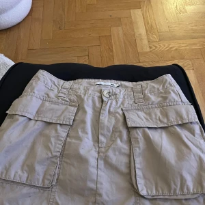 Beige cargo kjol med fickor -  kjol med  praktiska fickor framtill. Passar bra till både t-shirt och blus!