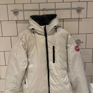 Frostgrå dunjacka från Canada Goose - Säljer en frostgrå dunjacka från Canada Goose i storlek L. Jackan är perfekt för kalla vinterdagar med sin varma och skyddande design. Den har en dragkedja framtill och en praktisk huva. Märket är känt för sin kvalitet och hållbarhet. Passar både till vardags och mer äventyrliga utflykter. 🧥❄️