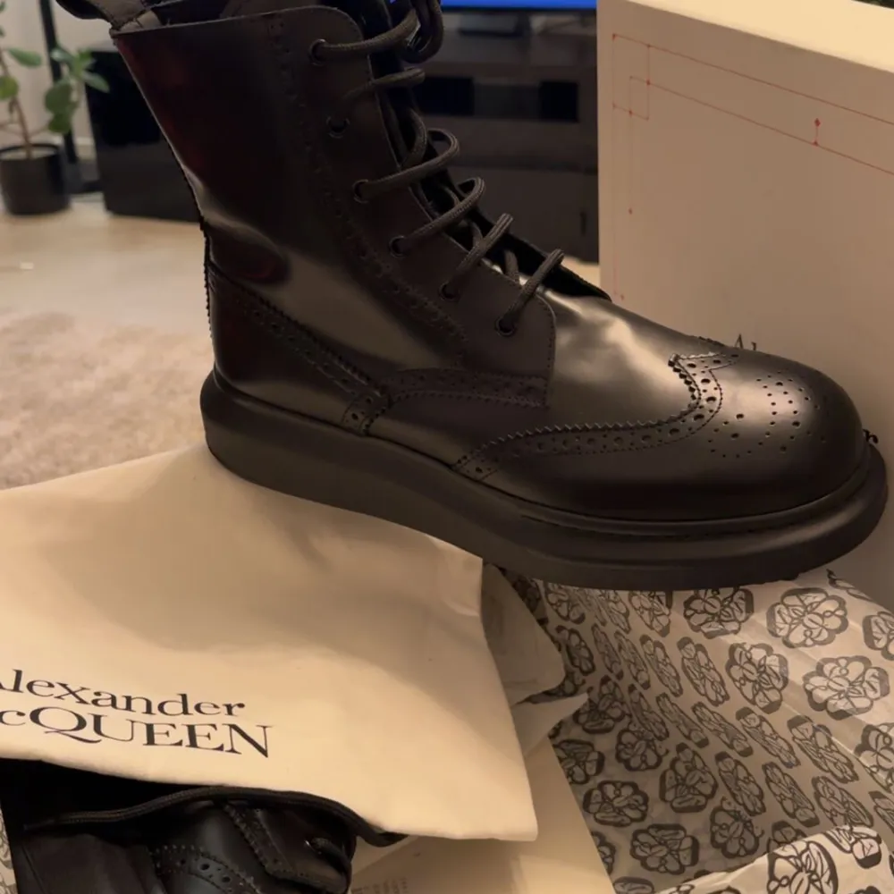 Säljer ett par svarta boots från Alexander McQueen i nytt skick. De är tillverkade i skinn med snygg snörning och broderade detaljer. Perfekta för höst och vinter, dessa boots är både stiliga och praktiska. Kommer med originalförpackning och dustbag.. Kengät.