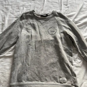 Grå sweatshirt från Peak Performance - Säljer en stilren grå sweatshirt från Peak Performance. Tröjan har en rund hals och långa ärmar, perfekt för en avslappnad look. Den är i bra skick och har en liten logga på bröstet.