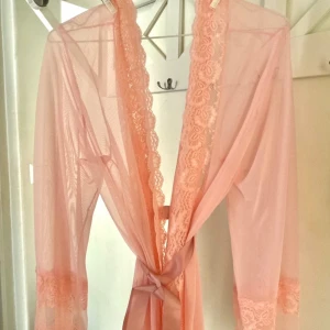 Rosa spets morgonrock  - Säljer en superfin rosa spets morgonrock med spetsdetaljer. Den är axelbandslös och har en knytning i midjan för en smickrande , materialet är lätt och luftigt, vilket gör den bekväm att bära hela dagen.🦢🧸