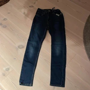 Mörkblå skinny jeans från H&M - Säljer ett par mörkblå skinny jeans från H&M i storlek 164. De är i bra skick och perfekta för både vardag och fest. Jeansen har en klassisk femficksdesign och är tillverkade i en bekväm denimblandning med 20% polyester för extra stretch. Passar perfekt till en avslappnad stil eller med en snygg topp för en mer uppklädd look.