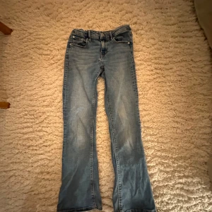 Blåa jeans från Gina Tricot - Säljer ett par snygga blå jeans från Gina Tricot i storlek 134.De är bootcut och lowaist. Jeansen är i bra skick och har en bekväm passform. Perfekta för skolan!