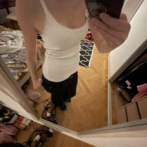 Vitt linne från Lefties - Säljer ett vitt linne från Lefties i storlek S. Det är i ribbat material med spetsdetaljer vid axelbanden och halsringningen. Perfekt för sommardagar eller som ett basplagg i garderoben. Använd få gånger och i mycket bra skick.