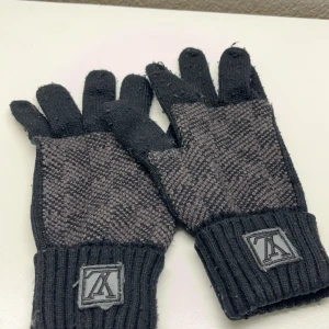 Svarta lv handskar - Snygga svarta lv handskar med ribbade muddar och en stilren logotyp på handleden. Perfekta för att hålla händerna varma under kalla dagar.