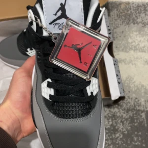 Nike Air Jordans i grått och svart - Snygga Nike Air Jordans i grått och svart med vita detaljer. Skorna har en ikonisk design med snörning och en synlig Air-enhet i sulan. Perfekta för sneakerheads som vill ha stil och komfort.