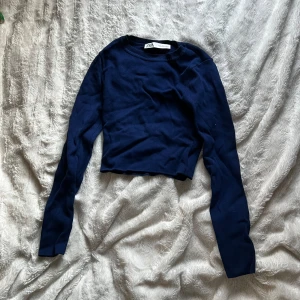 Mörkblå croppad tröja från Zara - Säljer en mörkblå croppad tröja från Zara. Tröjan har långa ärmar och är perfekt för en stilren look. Passar bra till både jeans och kjol. Perfekt för höst och vår!