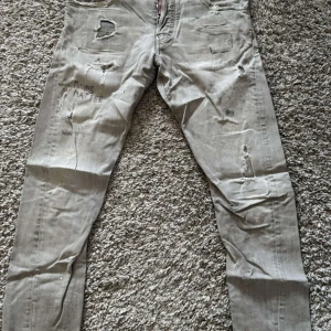 DSQUARED2 - Snygga grå jeans med coola slitningar och broderad text på framsidan. De har en klassisk femficksdesign och en bekväm passform. Perfekta för en avslappnad stil.