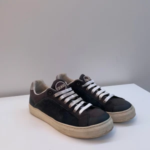 Mörk blåa sneakers från Colmar - Snygga svarta sneakers från Colmar med vita snören och en beige sula. Skorna har en klassisk design med en rund tå och är perfekta för en avslappnad stil.