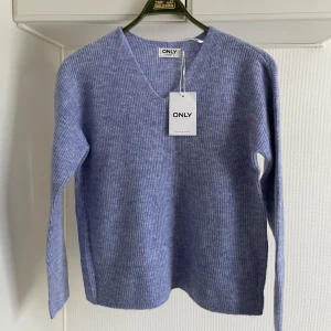 Ljusblå stickad tröja från ONLY M OANVÄND - Säljer en ljusblå stickad tröja från ONLY med v-ringning. Tröjan har långa ärmar och en mjuk, ribbad textur. Perfekt för kyliga dagar!