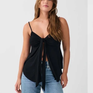 Linne från Gina  - Trendig svart ärmlös topp med smala axelband och knyt framtill. Perfekt för en stilren och avslappnad look. Aldrig använd💕