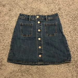 Jeanskjol med knappar - Snygg jeanskjol från &Denim med knappar framtill och två praktiska fickor. Perfekt för en avslappnad stil.