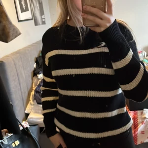 Svart och vit randig stickad tröja - Säljer en svart och vit randig stickad tröja med långa ärmar. Perfekt för en avslappnad stil med ribbade detaljer vid hals och ärmslut. En klassisk och bekväm tröja för kyligare dagar.