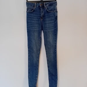Blå skinny fit/curved high waist jeans - Snygga blå skinny fit/curved high waist jeans i storlek 34. Använda någon enstaka gång men gillade inte hur de satt. Original pris är 199kr köpta på Gekås 