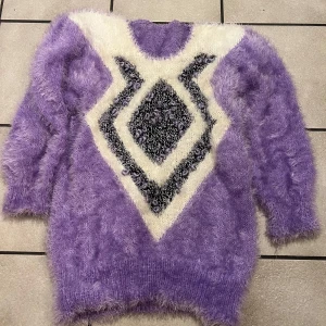 Lila mohair  tröja med geometriskt mönster - Säljer en unik lila mohair tröja med ett iögonfallande geometriskt mönster i vitt och svart. Tröjan har långa ärmar och är perfekt för att hålla sig varm och stilren under kyliga dagar.