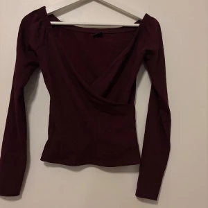 Vinröd omlottopp från Gina Tricot - Snygg vinröd omlottopp från Gina Tricot med långa ärmar. 