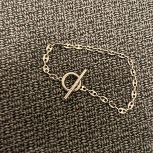 Silverfärgat armband med T-bar lås från All Blues - Elegant silver armband med en stilren kedja och T-bar lås. Liten deffekt som fixats med ståltråd som knappt syns, därför priset.