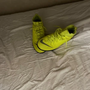 Gula fotbollsskor från Nike - Snygga gula fotbollsskor från Nike med svart logga och snörning. Perfekta för fotbollsplanen med sin iögonfallande färg och design. Är för inomhus fotboll och grus fotboll. Pris kan sänkas och diskuteras 