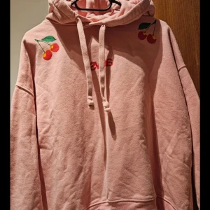 Rosa hoodie - Superfin färg med körsbärs-tryck, dock lite nopprig men fyller fortfarande sin funktion