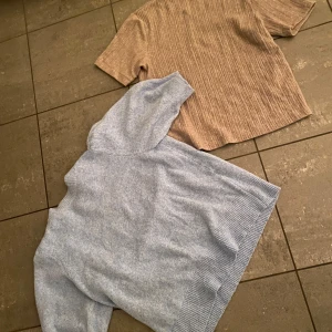 Blå och beige tröja - Två tröjor till salu: en ljusblå stickad tröja  och en beige kortärmad tröja med ribbat mönster. Perfekta för olika tillfällen och stilar. Säljer båda tillsammans. Pris kan diskuteras! Beiga står storlek L men är i samma storlek som blåa i verkligheten som är S.
