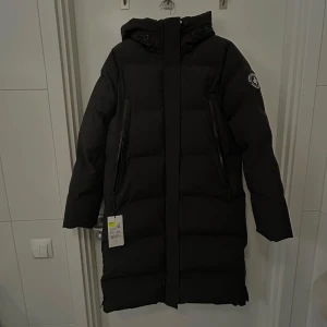 Svart vinterjacka från Cross Sportswear - Lång svart och varm vinterjacka från cross sportswear i storlek S. Helt ny med lappen kvar. Köpt för 1199kr. Köpte två i olika storlekar och hann inte lämna tillbaka denna🥲.   Enorma fickor som går att justera storleken på när man drar dragkedjan åt de olika hållen. Dragkedja på vardera sida av jackan längst ner om man vill öppna upp lite.   Otrooooligt varm, har haft min i rätt storlek nu och är sååå nöjd!!   Öppen att förhandla pris vill bara få igen lite💕