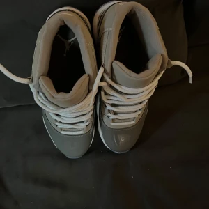 Grå Nike Air Jordans 11 - Snygga grå Nike Air Jordans med vit sula och klassisk snörning. Skorna har en stilren design med hög ankel och är perfekta för sneaker-älskare.