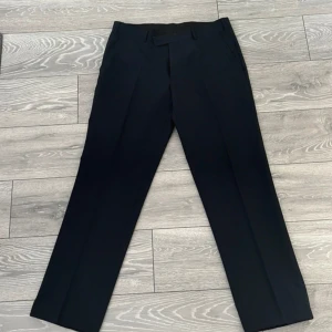 Kostymbyxa - Snygga marinblå kostymbyxor från Dressmann i klassisk design. Byxorna har en rak passform med diskreta pressveck och stängs med dragkedja och knapp. Perfekta för en stilren look. Dessa är aldrig använda, ny pris: ca 600kr 🍸 W34, L32 (herrstorlek)