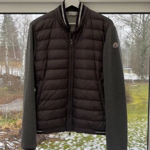 Grå quiltad jacka från Moncler - Snygg grå Moncler cardigan. Jackan har en stilren design med ribbade detaljer vid kragen och ärmsluten. Perfekt för våren! Pris går att diskutera. L men passar M.  Såklart äkta!