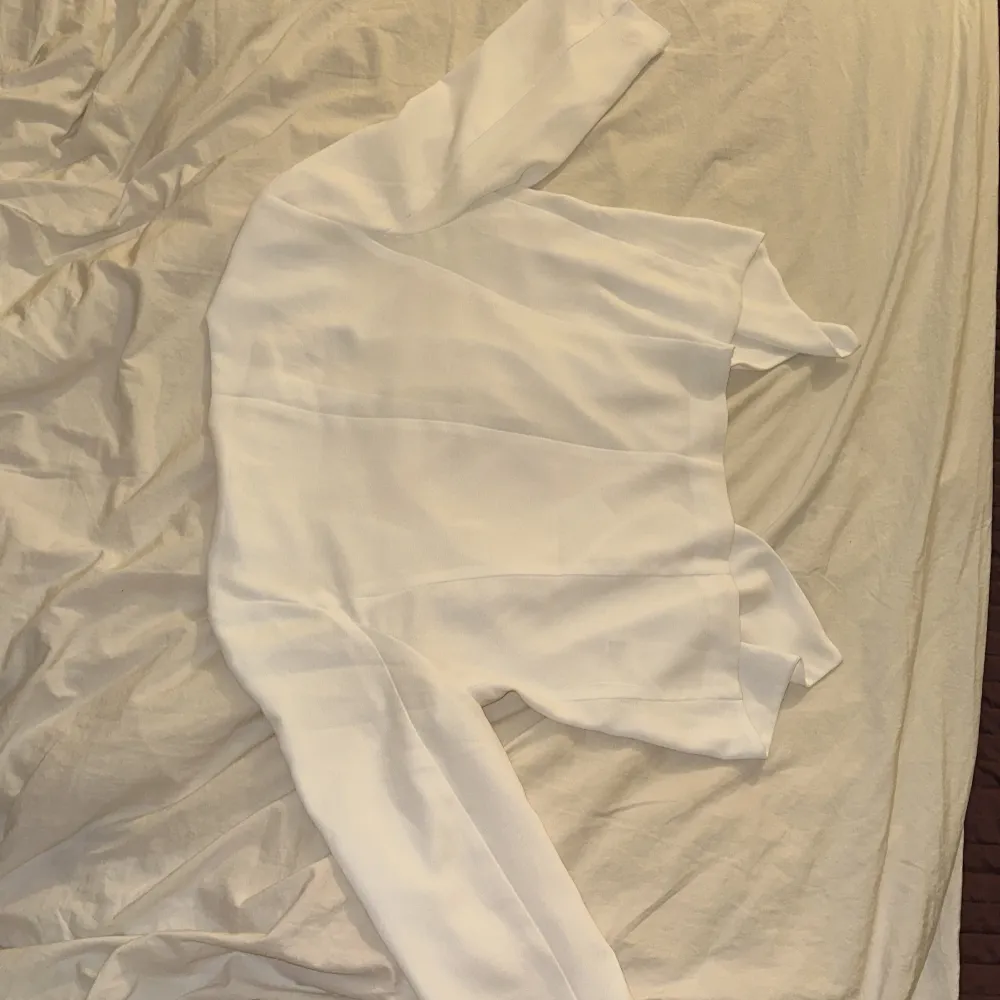 Säljer en stilren vit trekvartsärmad topp från Cubus. Perfekt för en minimalistisk look. Toppen har en enkel design som faller enkelt på kroppen och kan både kläs upp och kläs ner. Neuletakit & Villapaidat.