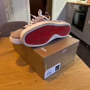 Beige sneakers från Christian Louboutin - Snygga beige sneakers i mocka från Christian Louboutin med den ikoniska röda sulan. Size 42 tts fint skick och låda samt tillbehör finns tvättas innan frakt endast använda fåtal gånger