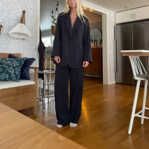 Mörkblå randig kostym - Snygg mörkblå kostym med vita ränder. Kavajen har en klassisk passform med knappar framtill och byxorna är raka och bekväma. Perfekt för en stilren look. Kavaj xs/s. Byxa 38