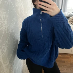 Stickad tröja med dragkedja - Säljer en mysig blå stickad tröja med hög krage och dragkedja framtill. Tröjan har ett snyggt flätmönster och långa ärmar. Den är väldigt varm, så perfekt för kyliga dagar☺️