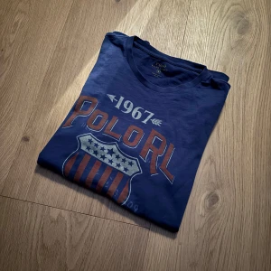 Blå t-shirt från Polo Ralph Lauren - As cool och unik tisha från Ralph lauren. Storlek S skitbra passform. Inga defekter som ny! Hör av dig vid frågor eller liknande🤝