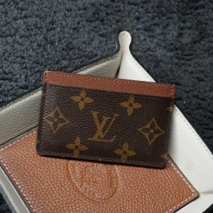 Vintage Louis Vuitton korthållare - Snygg och stilren brun plånbok från Louis Vuitton med det klassiska monogrammönstret. Perfekt för att hålla dina kort organiserade med stil. Skicket är som nytt, 9/10. Priset är inte hugget i sten och kan diskuteras, Om du har några frågor så tveka inte på att hojta till! /Rivi’e Reventio
