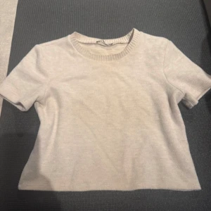 Beige kortärmad tröja från Zara - Säljer en stilren beige tröja från Zara med korta ärmar och rund halsringning. Perfekt för en enkel och snygg look. Passar bra till både jeans och kjol.