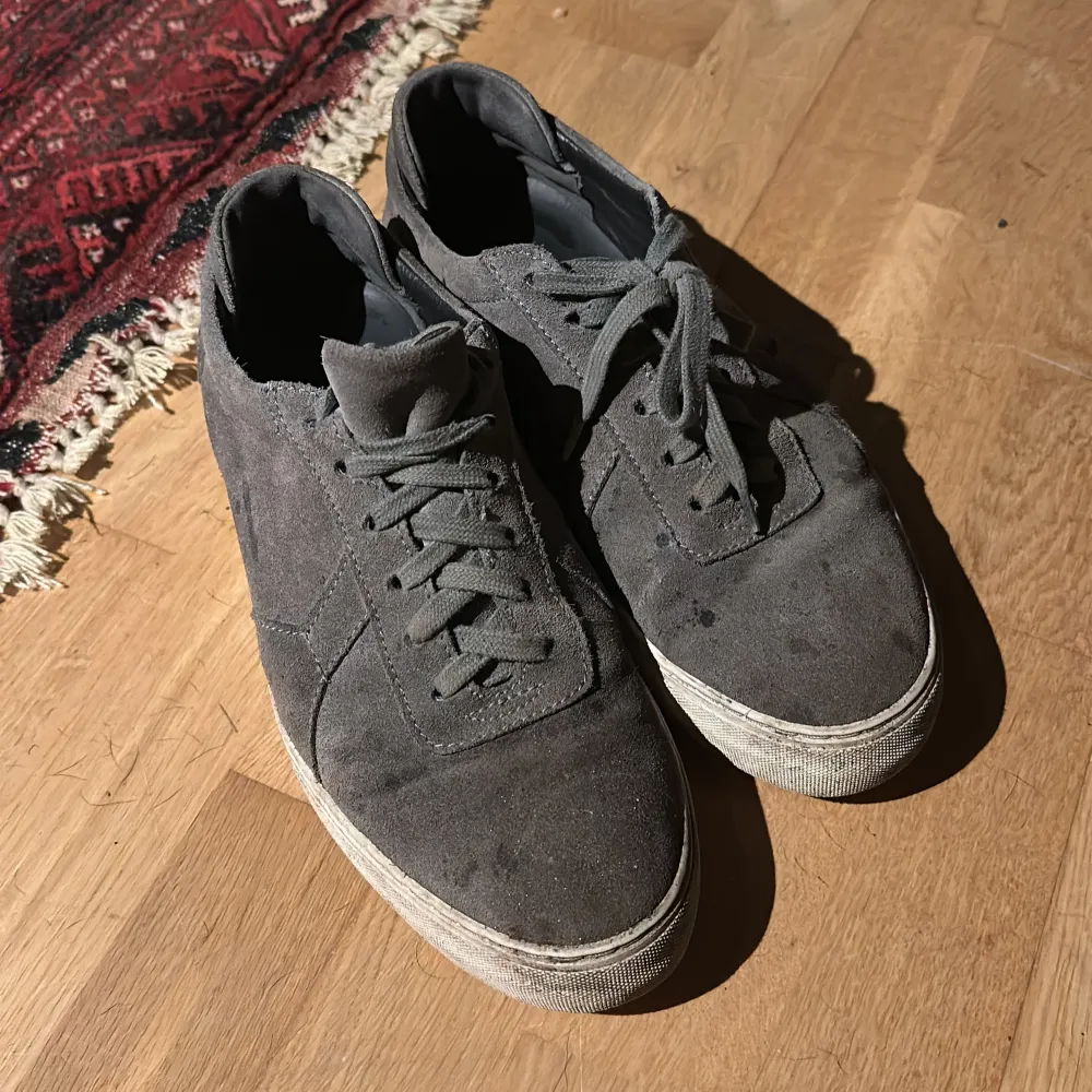 Säljer ett par stilrena Axel Arigato sneakers i grått – en minimalistisk och modern design som passar till allt! Skorna är använda och har lite smuts på sig just nu, men självklart kommer jag att tvätta dem och leverera dem helt rena vid köp. Perfekta för både vardag och mer uppklädda tillfällen. Kvaliteten är fantastisk, detta är en chans att fynda! Storlek 43/44 Skicka ett meddelande vid intresse eller om du har fler frågor!. Kengät.