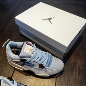 Nike Air Jordans i ljusblå mocka - Säljer ett par stilrena Nike Air Jordans i ljusblå mocka med svarta och vita detaljer. Skorna har snörning och en ikonisk design med Jumpman-loggan på sulan. Perfekta för sneaker-entusiaster!