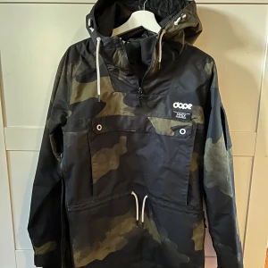 Camouflage skidjacka från Dope - Snygg camouflage skidjacka från Dope med justerbar huva och dragkedja. Perfekt för slalomåkning