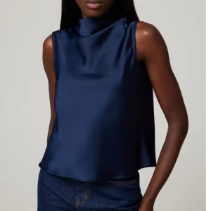 Mörkblå ärmlös topp - Elegant mörkblå ärmlös topp i satin med hög krage. Perfekt för en stilren look. Nypris 300kr