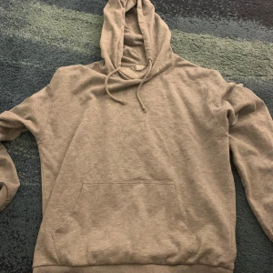 Grå hoodie i ekologisk bomull - Säljer en bekväm grå hoodie i ekologisk bomull från märket C. Den har en klassisk design med känguruficka och justerbar huva med dragsko. Perfekt för en avslappnad stil.