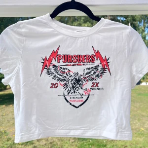 Vit croppad t-shirt med tryck  - Vit croppad t-shirt med tryck på bröstet. T-shirten är i storlek L men är liten i storlek då den passar bra till mig som har S. Skulle även passa till storlek M då den sitter lite löst på mig 🌸  (ALDRIG ANVÄND)  Längd: 40 cm Axel: 37 cm Byst: 87 cm