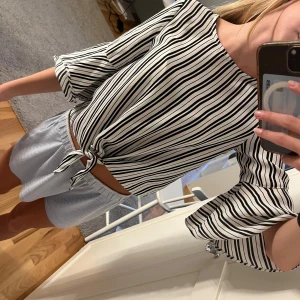 Randig blus från Lindex - Säljer en superfin randig blus från Lindex i svart och vitt. Den har trekvartsärmar med volangdetaljer och en knytning framtill. Perfekt för både vardag och fest!