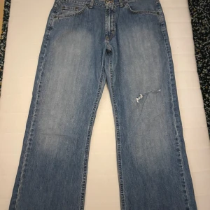 Blå jeans från Mc. Gordon - Säljer ett par blå jeans från Mc. Gordon i en skön comfort fit. De är tillverkade av 100% ring spun denim vilket gör dem både slitstarka och bekväma. Jeansen har en klassisk femficksdesign och en liten reva på framsidan för en avslappnad look.